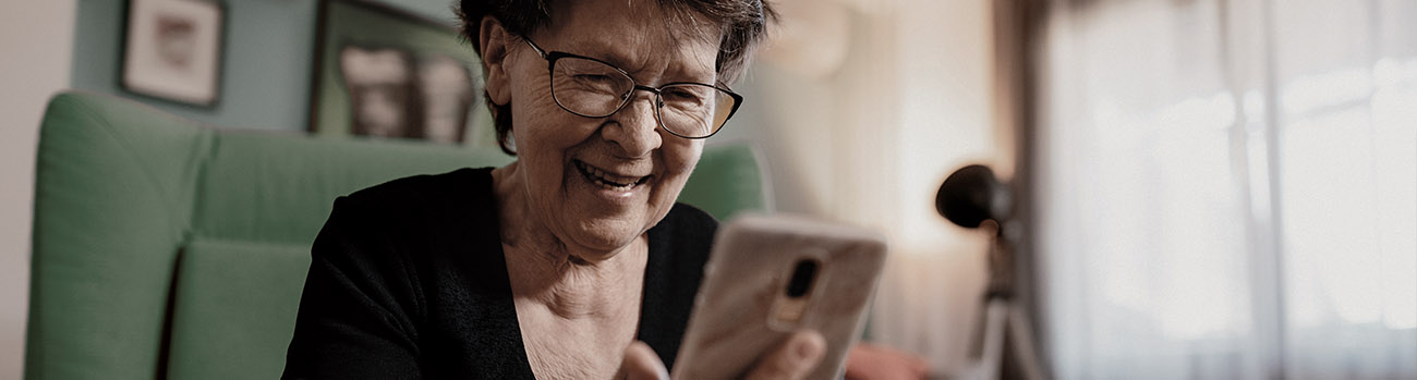 Older woman smiling and  looking at her mobile phone
