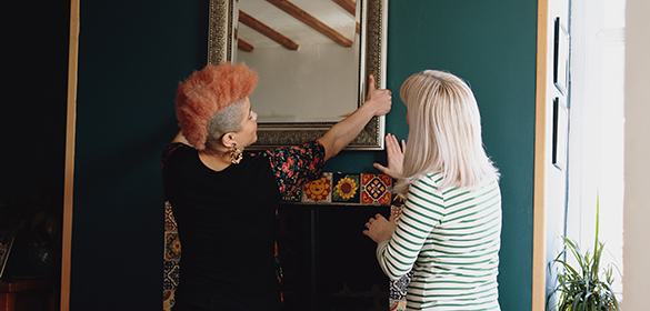 Two women hanging a picture frame